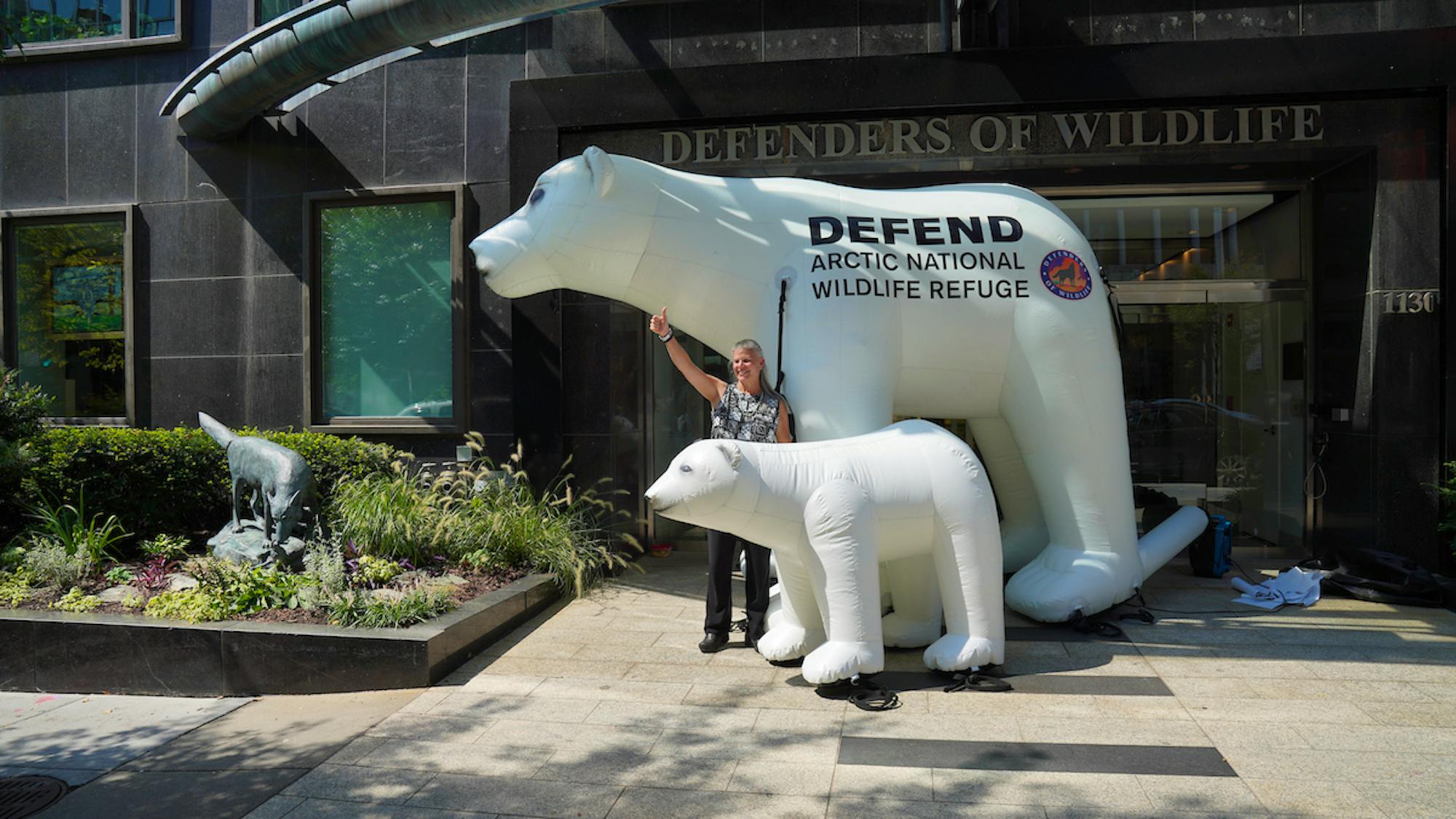 Jamie with polar bears thumbs up in front of HQ