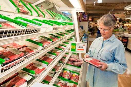 A shopper examines a package of meat in a grocery store 