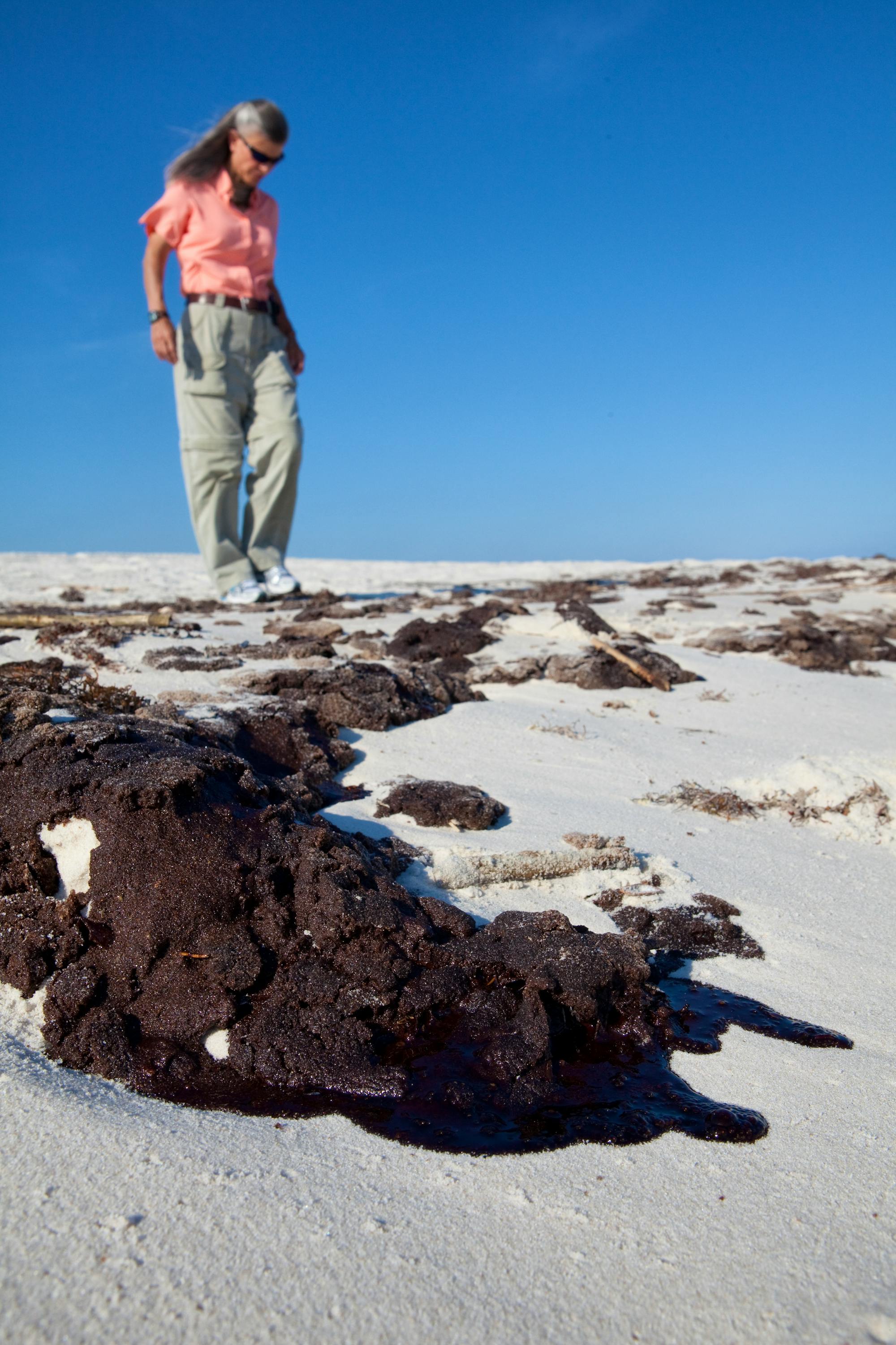 Jamie Rappaport Clark on the beach in the Gulf after the BP oil spill looking at washed up oil