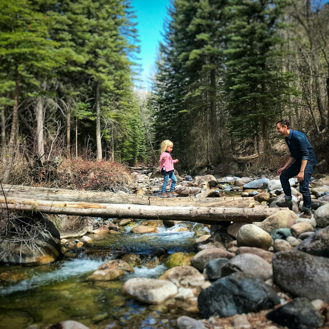 Dad and daughter hiking through woods across river