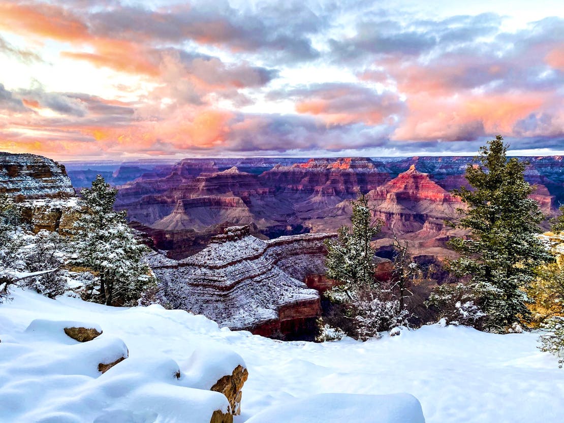 A pink sunset over the snow-covered rim of the Grand Canyon