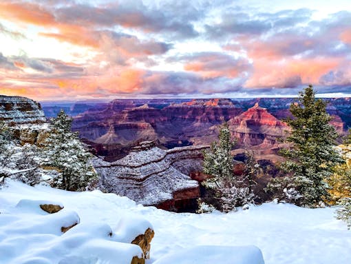 A pink sunset over the snow-covered rim of the Grand Canyon