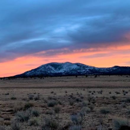 Sunset over the Elk Mountains in the distance from a desert landscape