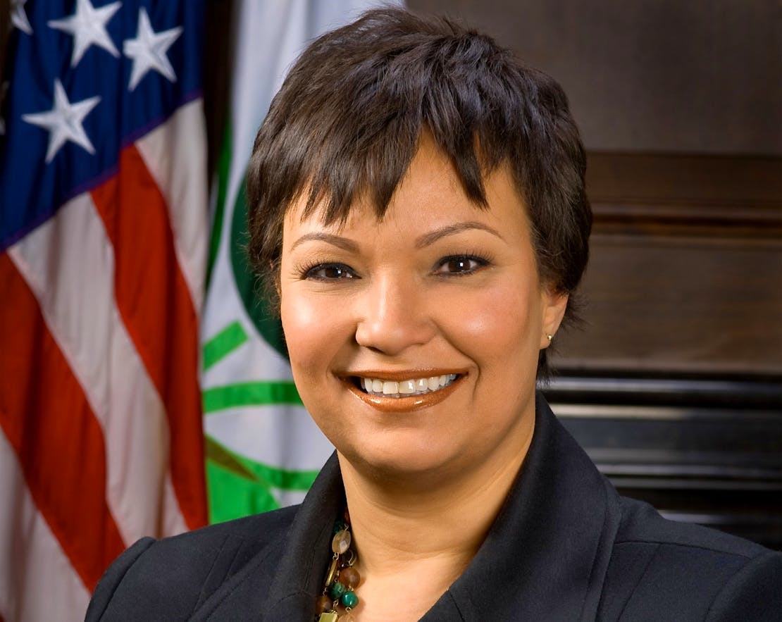 Lisa P. Jackson sitting in front of a folded down U.S. flag and a white flag with the EPA symbol in 2009.