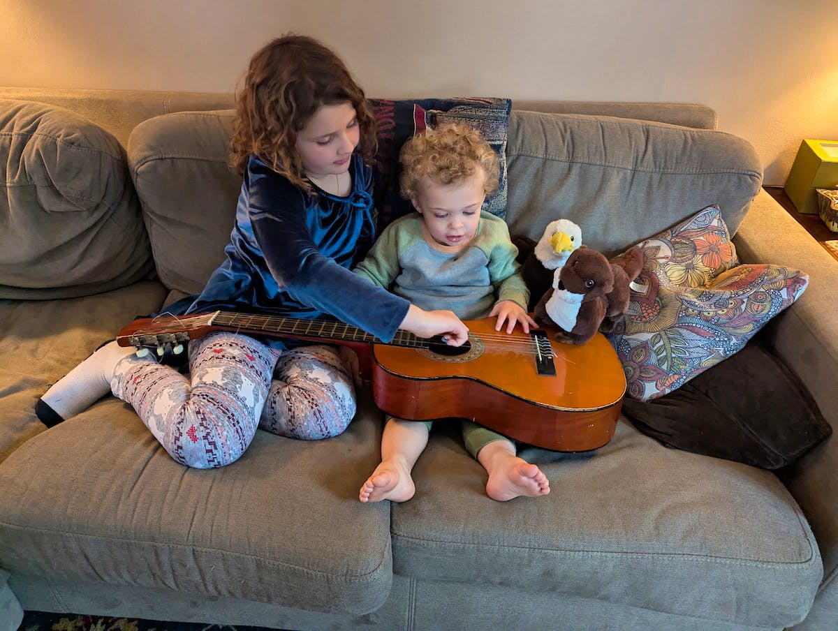 kids playing with guitar and plushie
