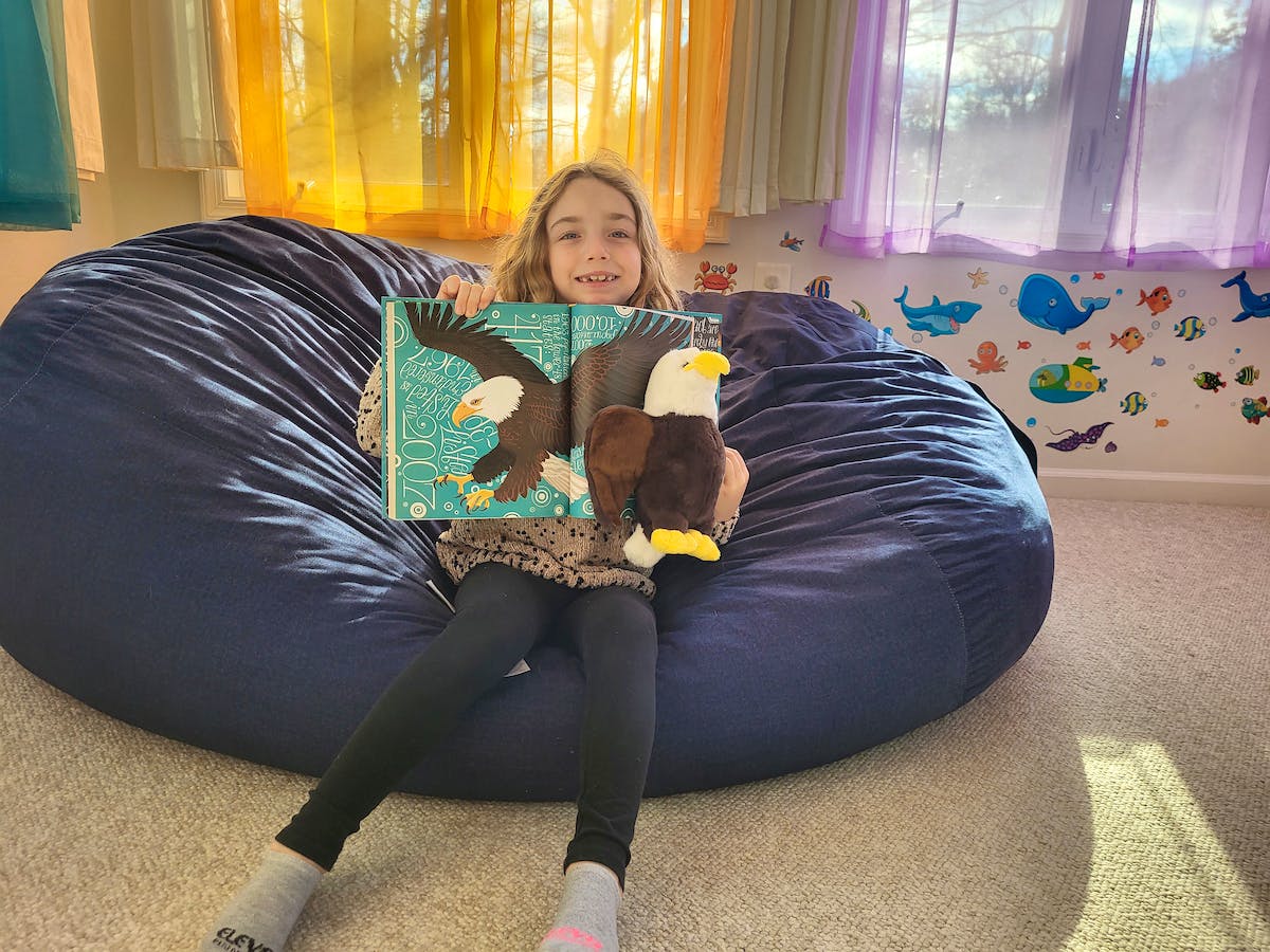 girl with bald eagle plushie and book 