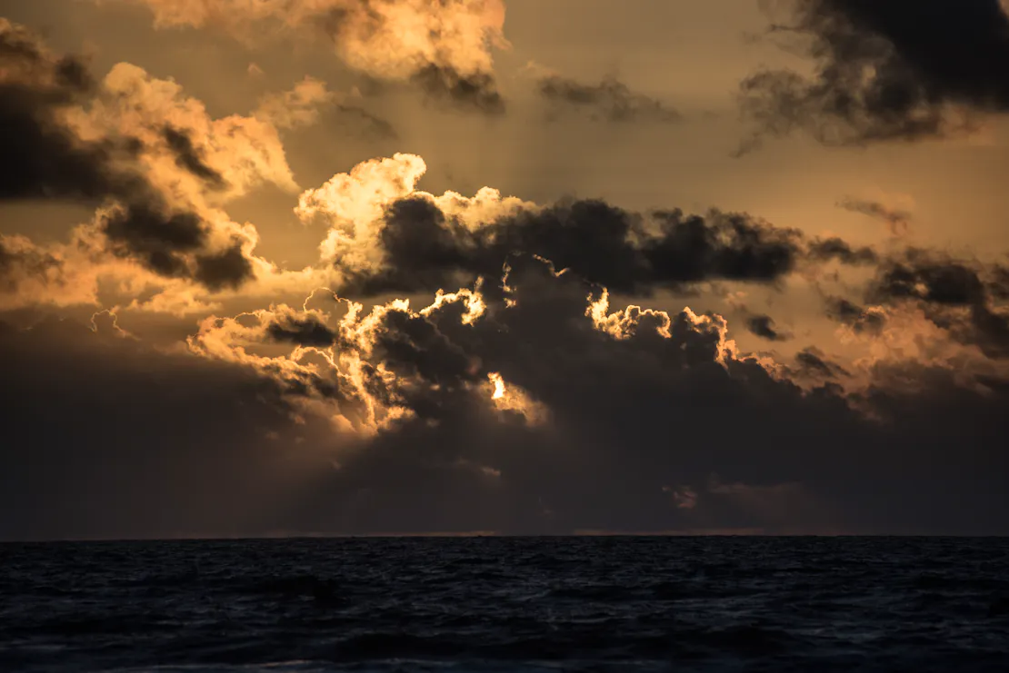 The sun feebly attempts to break from the clouds over the water.