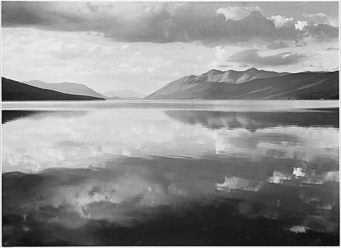McDonald Lake at Glacier National Park with mountains on the horizon line and clouds above.