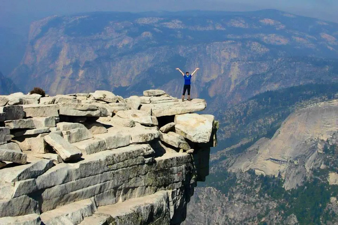 California Director, Pam Flick, stands on an outcropping atop Half Dome Mountain in Yosemite National Park.