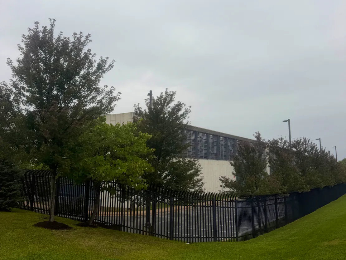 A data center behind a fence and trees in Virginia.